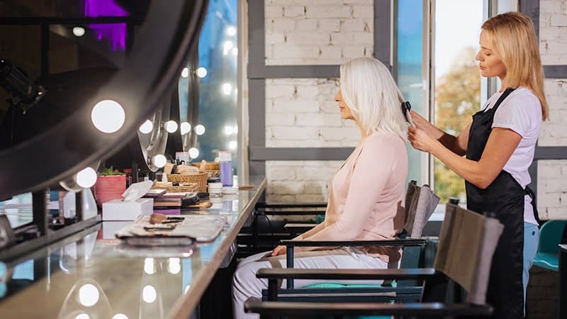 Client having her hair styled in front of a SalonTime-branded mirror